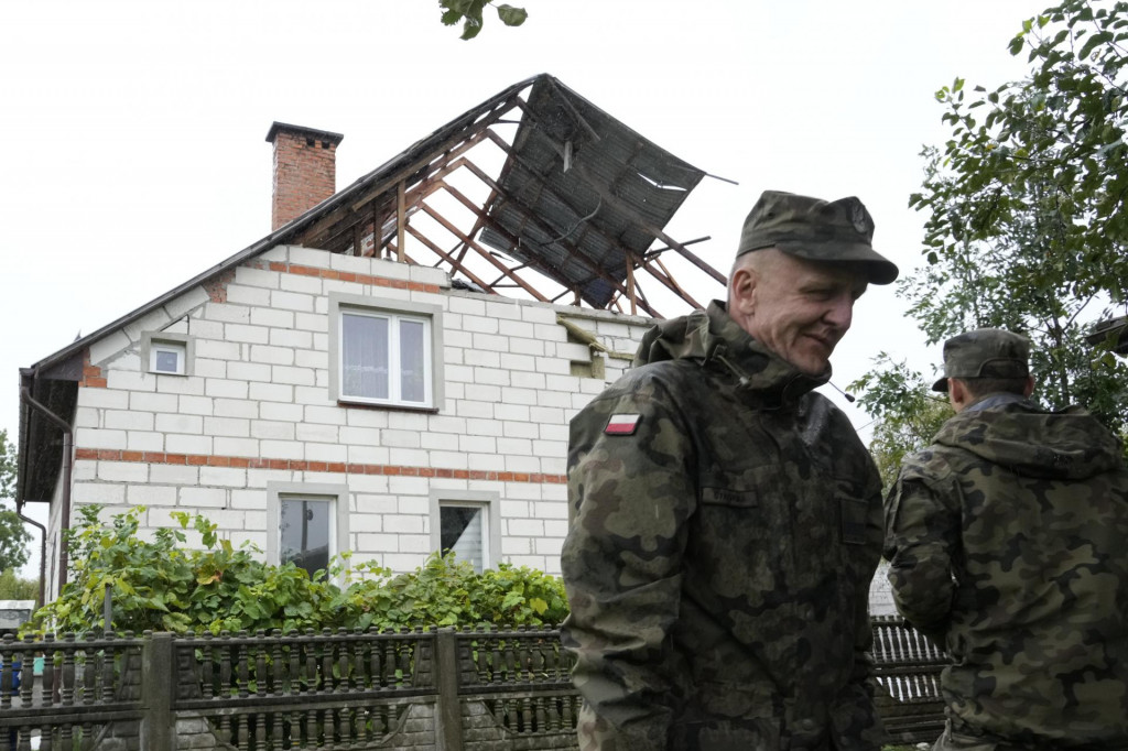 Na snímke príslušníci teritoriálnej obrany stoja pri obytnom dome, ktorého strechu poškodili úlomky jedného z ruských dronov v poľskej obci Wyryki v Lublinskom vojvodstve. FOTO: TASR/AP
