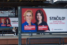 Žena sedí pri volebnom plagáte líderky koalície Stačilo! Kateřiny Konečnej a Jany Malacovej. FOTO: Reuters