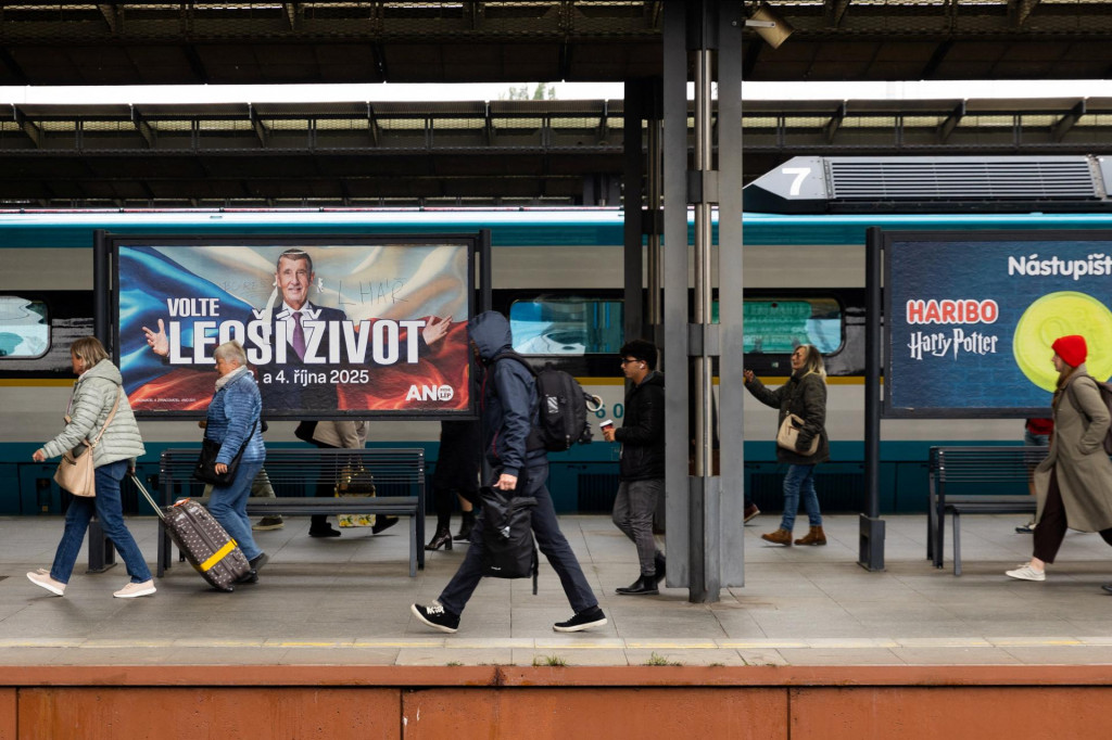 Cestujúci prechádzajú okolo volebného plagátu českého lídra strany ANO a bývalého českého premiéra Andreja Babiša. FOTO: Reuters