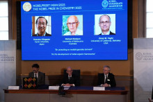 Na obrazovke sú zobrazení laureáti Nobelovej ceny za chémiu za rok 2025, Susumu Kitagawa, Richard Robson a Omar Yaghi.