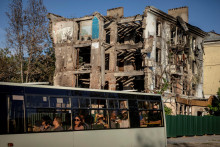Autobus prechádza okolo bytového domu, ktorý bol v júli tohto roku zničený ruskou raketou v meste Kramatorsk na frontovej línii. FOTO: Reuters