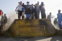 Protestujúci stoja na oceľovom kontajneri blokujúc cestu počas celonárodného protestu vedeného mládežou proti častým výpadkom prúdu a nedostatku vody v Antananarive na Madagaskare. FOTO: Reuters