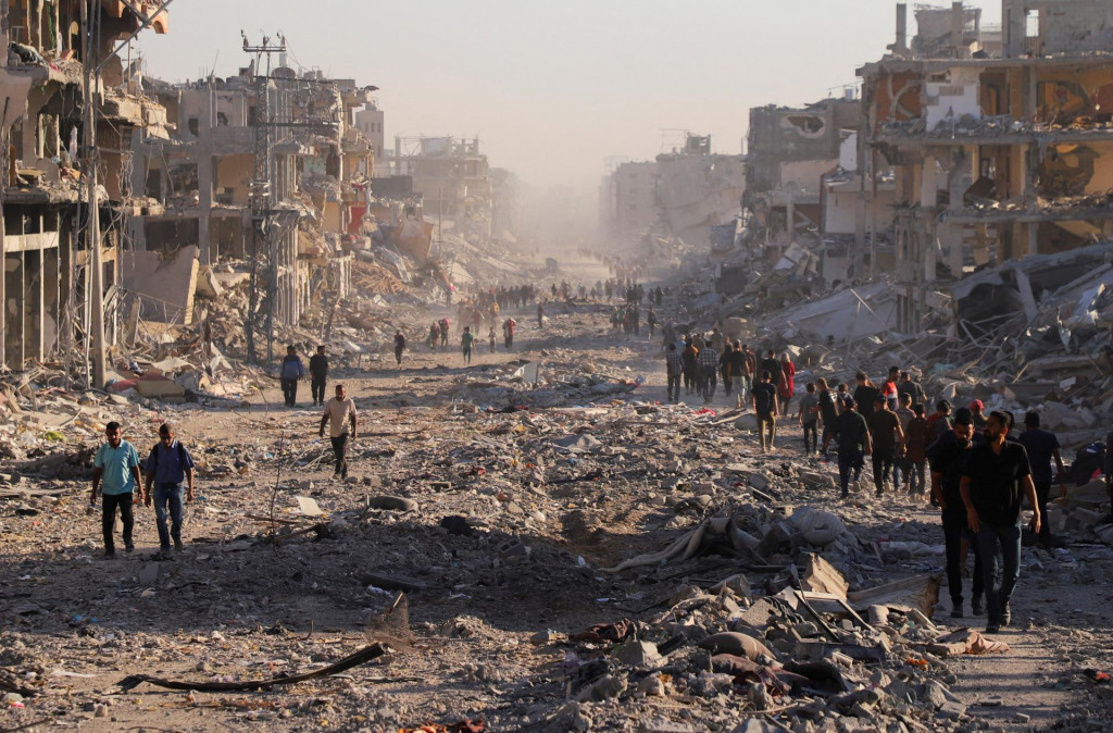 Palestínčania prechádzajú poškodenou štvrťou po izraelskej operácii po tom, čo izraelská vláda ratifikovala prímerie s Hamasom. FOTO: Reuters