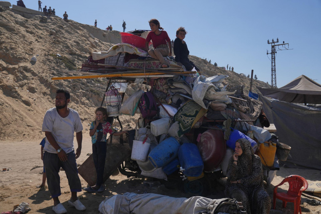 Vysídlení Palestínčania sedia a stoja vedľa svojich zbalených osobných vecí v centrálnej časti Pásma Gazy. FOTO: TASR/AP