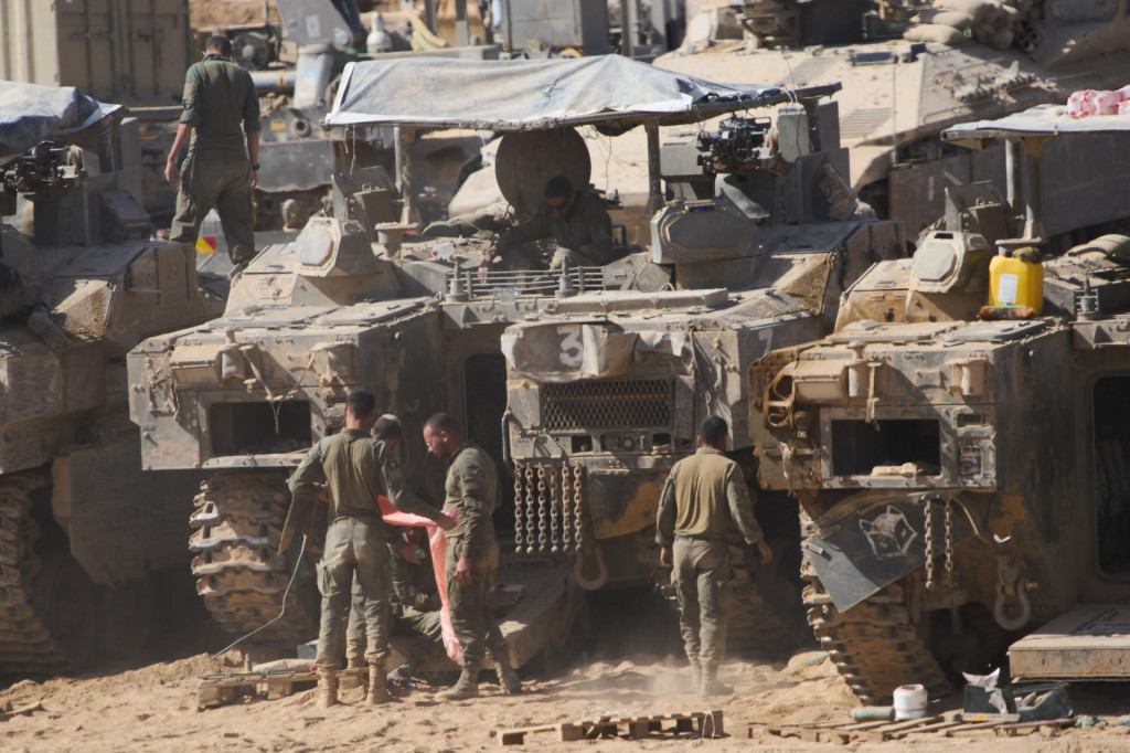 Izraelskí vojaci pracujú na svojich tankoch v hangári neďaleko hranice Izraela s Pásmom Gazy. FOTO: TASR/AP

