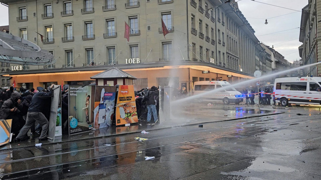 Propalestínskych demonštrantov postrekuje vodný kaňon počas demonštrácie v Berne. FOTO: Reuters/Raimond Lueppken
