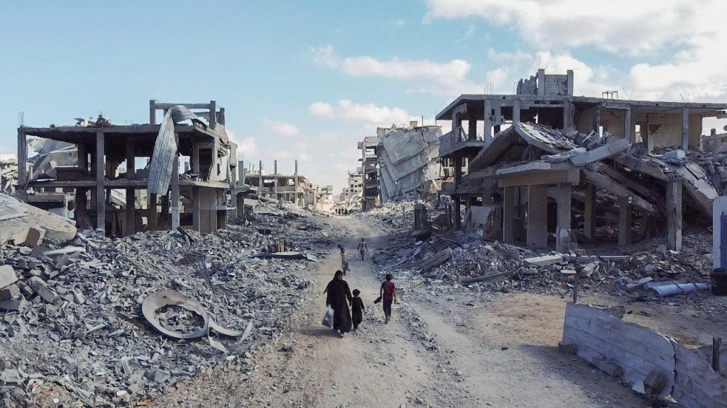 Ľudia prechádzajúci sa zničenou obytnou štvrťou v meste Gaza. FOTO: Reuters