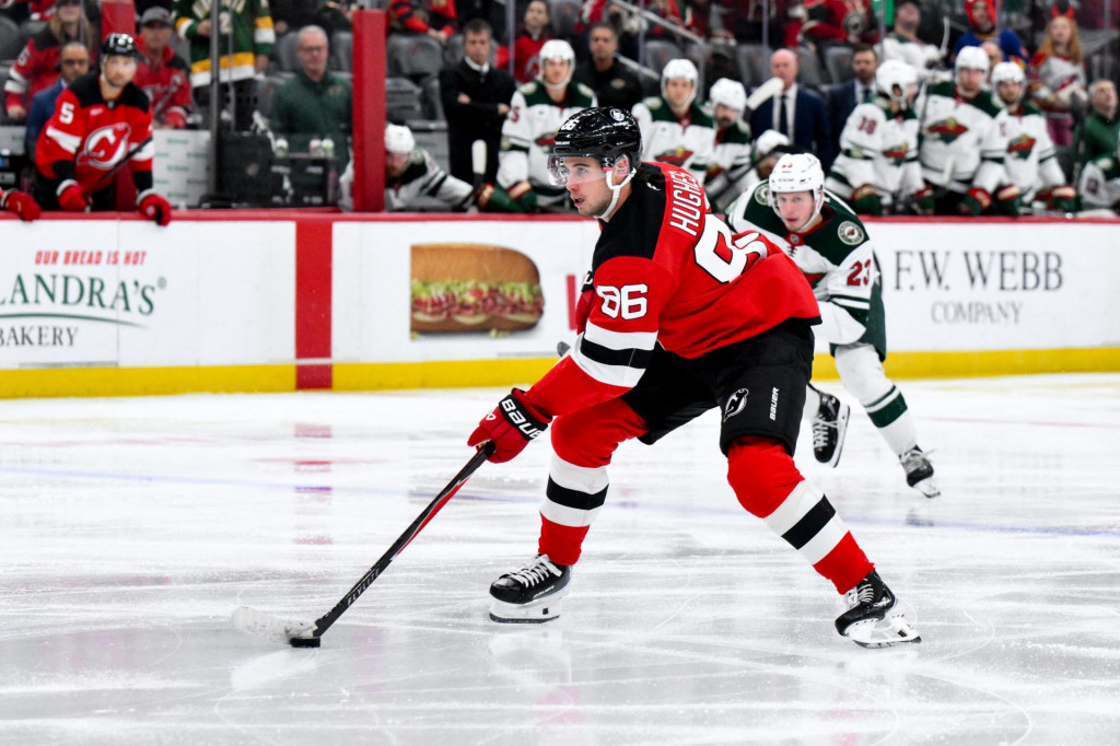 Center New Jersey Devils Jack Hughes (86) korčuľuje s pukom, zatiaľ čo ho bráni center Minnesoty Wild Marco Rossi (23) počas druhej tretiny. FOTO: John Jones/Imagn Images