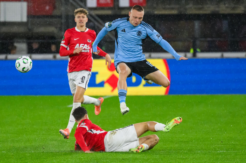 Na snímke zľava kapitán Sven Mijnans (Alkmaar), Nino Marcelli (Slovan) a dole Wouter Goes (Alkmaar) bojujú o loptu počas zápasu 2. kola ligovej fázy Konferenčnej ligy vo futbale AZ Alkmaar - ŠK Slovan Bratislava v holandskom meste Alkmaar vo štvrtok 23. októbra 2025. FOTO: TASR