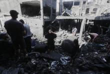 Palestínčania skúmajú trosky budovy zničenej počas izraelských leteckých útokov na tábor Al-Šati v meste Gaza. FOTO: TASR/AP