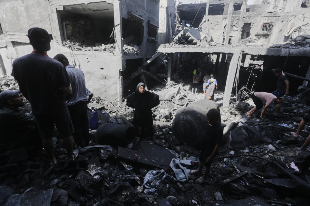 Palestínčania skúmajú trosky budovy zničenej počas izraelských leteckých útokov na tábor Al-Šati v meste Gaza. FOTO: TASR/AP