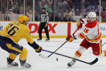 Center Calgary Flames Morgan Frost (16) strieľa, zatiaľ čo obranca Nashville Predators Brady Skjei (76) bráni počas druhej tretiny. FOTO: Alan Poizner/Imagn Images