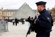 Príslušník francúzskej poriadkovej polície hliadkuje pri sklenenej pyramíde v múzeu Louvre. FOTO: Reuters