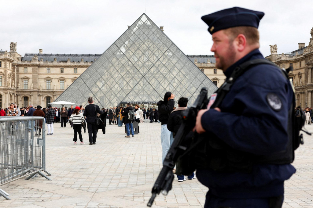 Príslušník francúzskej poriadkovej polície hliadkuje pri sklenenej pyramíde v múzeu Louvre. FOTO: Reuters