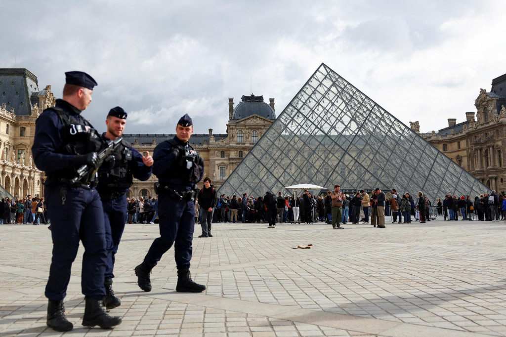 Príslušníci francúzskej poriadkovej polície kráčajú pri sklenenej pyramíde v múzeu Louvre. FOTO: Reuters