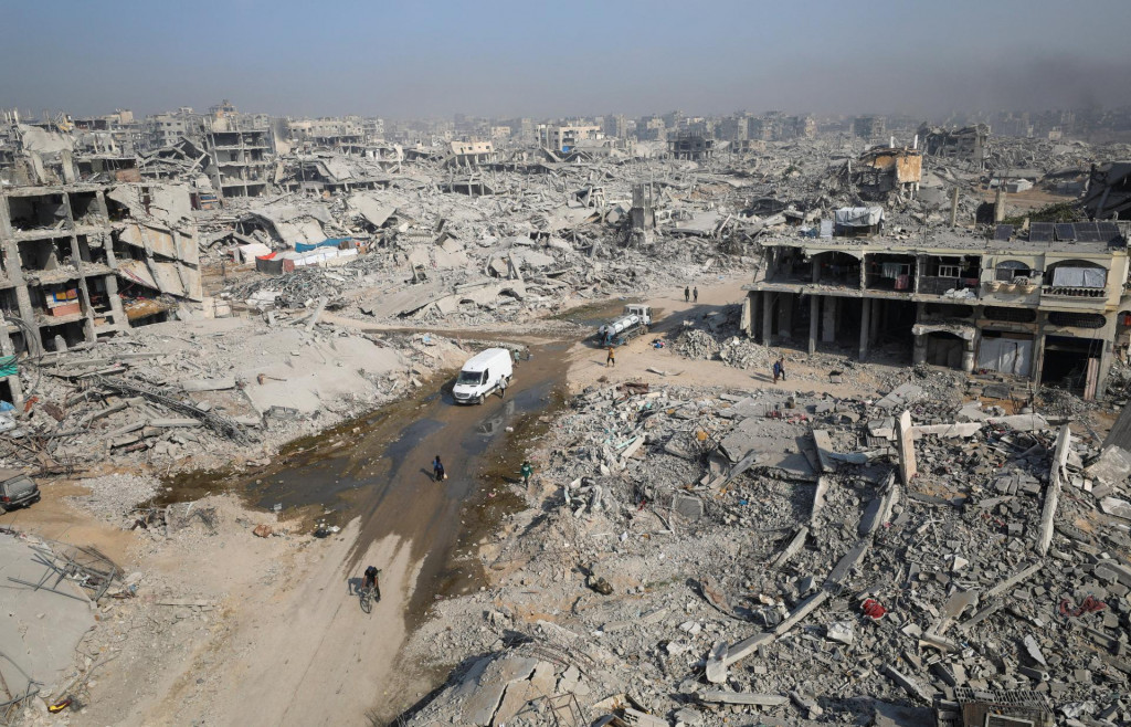 Palestínčania prechádzajú okolo trosiek zničených budov v meste Gaza. FOTO: Reuters