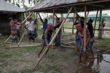 Ľudia pomáhajú pri obnove domu na bangladéšskom ostrove, kam sa obyvateľ spresťahoval kvôli erózii pôdy. FOTO: Reuters