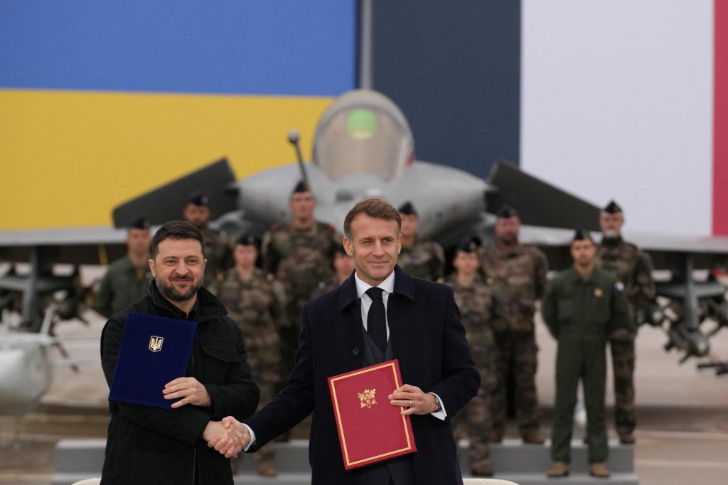 Francúzsky prezident Emmanuel Macron a ukrajinský prezident Volodymyr Zelenskyj si podávajú ruky po podpísaní dohody na leteckej základni Villacoublay. FOTO: Reuters
