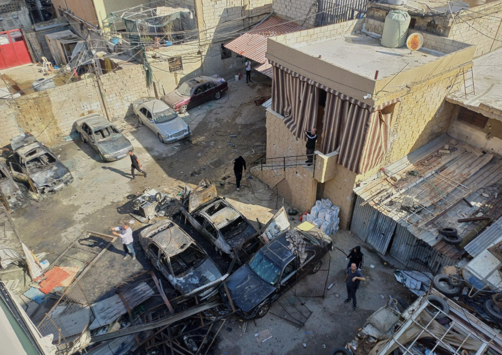 Palestínčania sa zhromažďujú pri zničených autách po izraelskom leteckom útoku na utečenecký tábor v prístavnom meste Sidon na juhu Libanonu. FOTO: TASR/AP