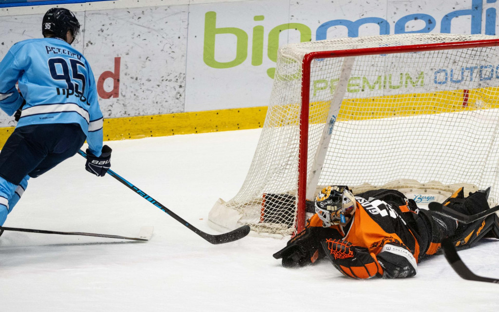 Na snímke zľava Jonáš Peterek (Slovan) dáva gól a vpravo brankár Vladimír Glosár (Michalovce) počas zápasu 22. kola Tisport ligy HC Slovan Bratislava – HK Dukla Michalovce. FOTO: TASR/Jakub Kotian
