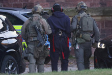 Polícia eskortuje Ukrajinca S.K. z vrtuľníka pred vypočutím s nemeckým federálnym prokurátorom. FOTO: Reuters