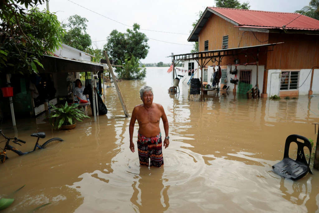 Muž sa pozerá na svoj rodinný dom, ktorý je zaplavený po silných dažďoch v Malajzii na hraniciach s Thajskom. FOTO: Reuters