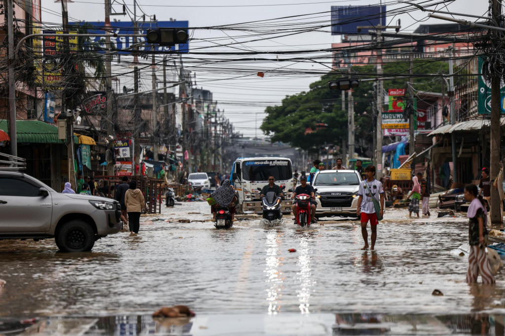 Ľudia doch&aacute;dzaj&uacute; do pr&aacute;ce cez zaplaven&uacute; oblasť v okrese Hat Yai v provincii Songchl&aacute; v Thajsku. FOTO: Reuters