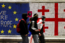 Podporovatelia gruzínskych opozičných strán prechádzajú okolo múru namaľovaného vlajkou Európskej únie a gruzínskou vlajkou počas protestu proti rozhodnutiu vlády pozastaviť rokovania o vstupe do Európskej únie (8. decembra). FOTO: Reuters