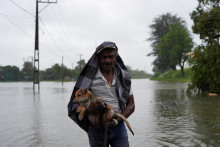 Muž so psom prechádza po zatopenej ulici vo Wellampitiyi na Srí Lanke. FOTO: Reuters