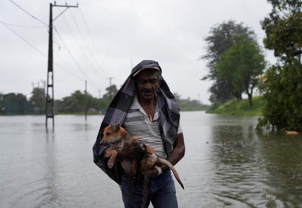 Muž so psom prechádza po zatopenej ulici vo Wellampitiyi na Srí Lanke. FOTO: Reuters