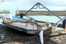 Kvetinový strapec leží pri lodi vedľa prístavu, kam ľudí zmietlo rozbúrené more. FOTO: Reuters/Forta