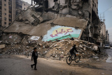 Palestínske deti prechádzajú cez ulicu okolo zničenej budovy v meste Gaza. FOTO: TASR/AP