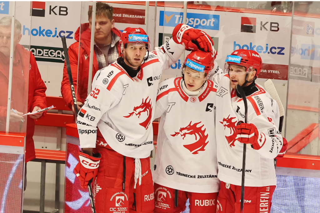 Třineckí obrancovia Martin Marinčin (vľavo) a Marian Adámek blahoželajú Matejovi Kubiesovi k prvému extraligovému gólu. FOTO: MAFRA/Jiří Seidl