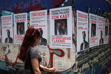 Žena prechádza okolo predvolebných plagátov proti prezidentskému kandidátovi Josému Antoniovi Kastovi a argentínskemu prezidentovi Javierovi Mileimu, na ktorých je nápis „Naša budúcnosť je v ohrození“, pred druhým kolom prezidentských volieb v Santiagu v Čile. FOTO: REUTERS