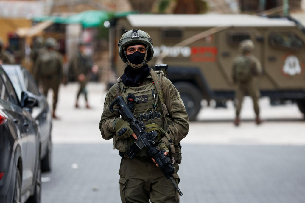 Izraelsk&yacute; vojak stoj&iacute; na str&aacute;ži so zbraňou počas t&yacute;ždennej prehliadky osadn&iacute;kov na Izraelom okupovanom Z&aacute;padnom brehu Jord&aacute;nu. FOTO: Reuters