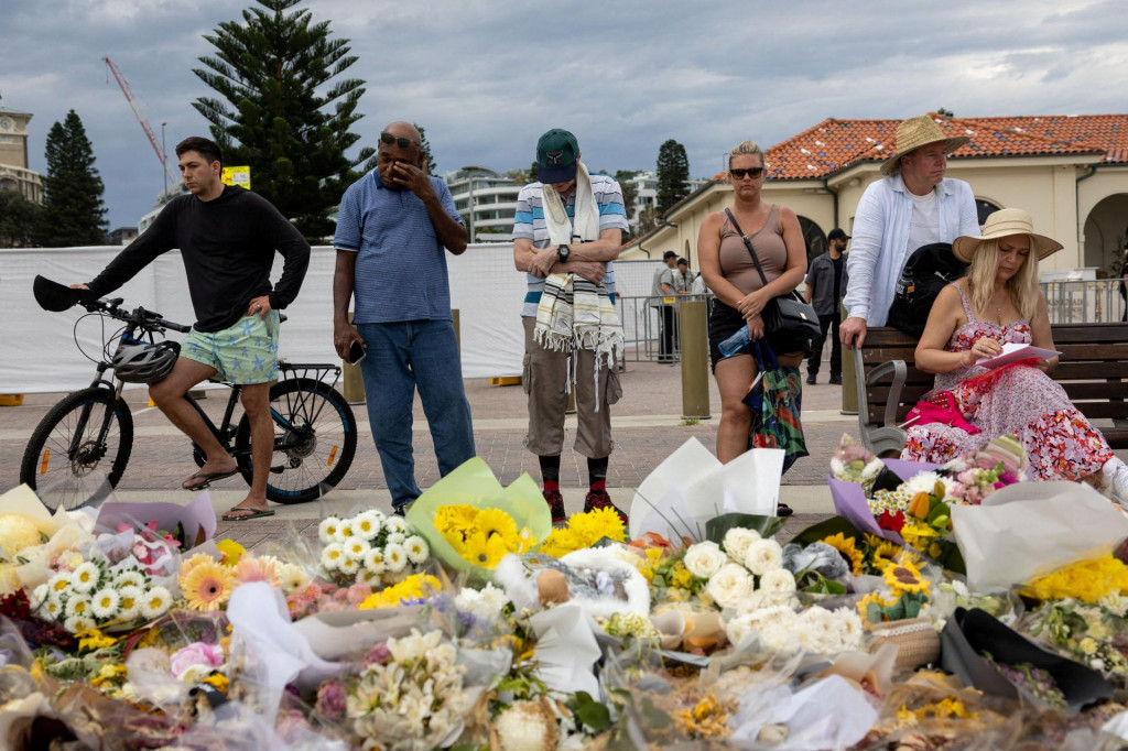 Ľudia sm&uacute;tia pri kvetinov&yacute;ch poct&aacute;ch za obete a pozostal&yacute;ch po masovej streľbe počas židovskej oslavy Chanuky na pl&aacute;ži Bondi Beach v Sydney. FOTO: Reuters