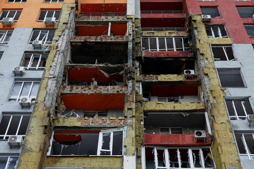Obyvatelia kyjevskej bytovky na z&aacute;bere z 27. decembra odprat&aacute;vaj&uacute; trosky po &uacute;toku jedn&eacute;ho zo stoviek rusk&yacute;ch dronov. FOTO: Reuters