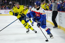 Slovensk&yacute; hokejista Filip Kovalč&iacute;k  a hr&aacute;č &Scaron;v&eacute;dska Loke Krantz bojuj&uacute; o puk v z&aacute;pase na MS hr&aacute;čov do 20 rokov v americkom meste St. Paul. FOTO: TASR/AP