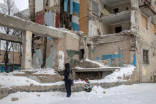 Žena stoj&iacute; pri proviz&oacute;rnom pam&auml;tn&iacute;ku, kde bytov&yacute; dom v Kyjeve bol zasiahnut&yacute; ruskou raketou. FOTO: Reuters