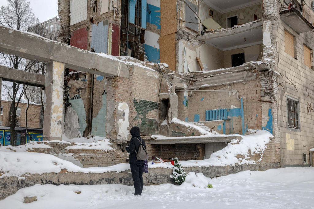 Žena stoj&iacute; pri proviz&oacute;rnom pam&auml;tn&iacute;ku, kde bytov&yacute; dom v Kyjeve bol zasiahnut&yacute; ruskou raketou. FOTO: Reuters
