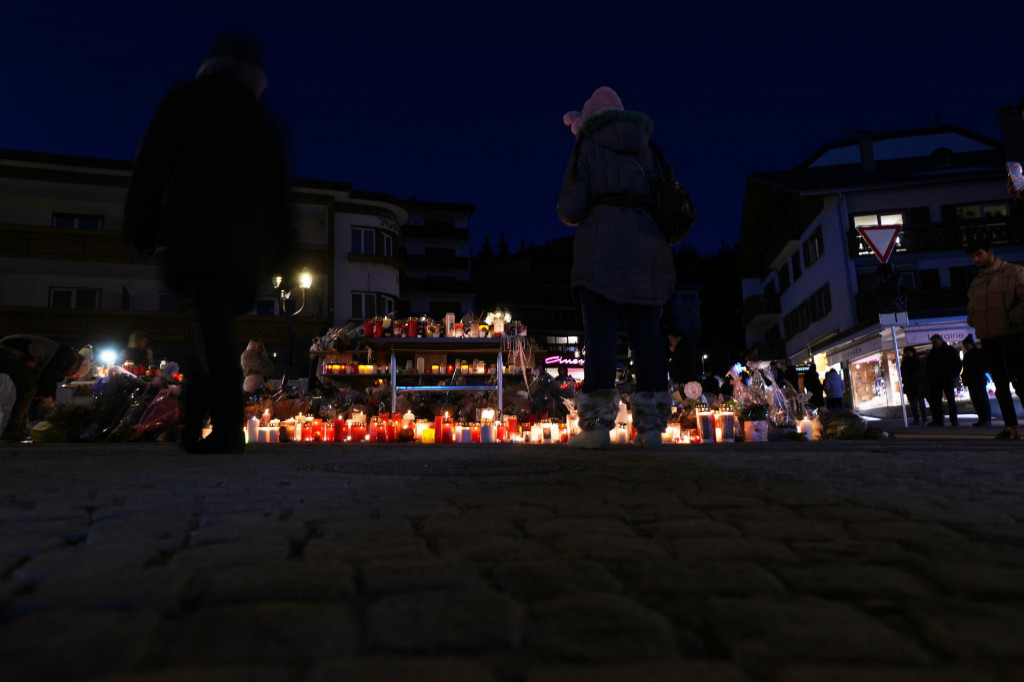 Ľudia zapaľuj&uacute; sviečky a klad&uacute; kvety na pamiatku obet&iacute; neďaleko vyhoren&eacute;ho baru Le Constellation v Crans-Montane vo &scaron;vajčiarskych Alp&aacute;ch 4. janu&aacute;ra 2026. FOTO: TASR/AP