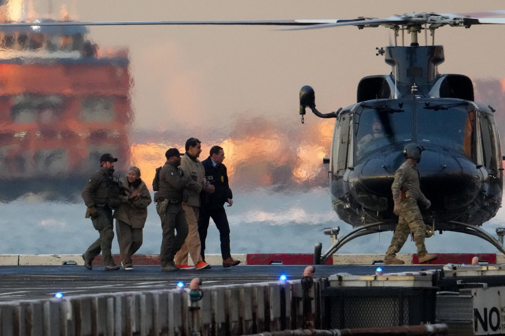 Pr&iacute;slu&scaron;n&iacute;ci org&aacute;nov činn&yacute;ch v trestnom konan&iacute; eskortuj&uacute; zajat&eacute;ho venezuelsk&eacute;ho prezidenta a jeho manželku Ciliu Floresov&uacute; z vrtuľn&iacute;ka. FOTO: REUTERS