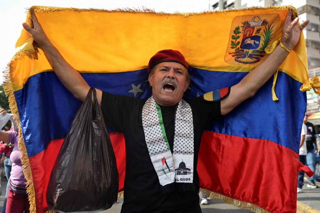 Podporovateľ Madurovho režimu drž&iacute; venezuelsk&uacute; vlajku počas pochodu za jeho prepustenie. FOTO: REUTERS