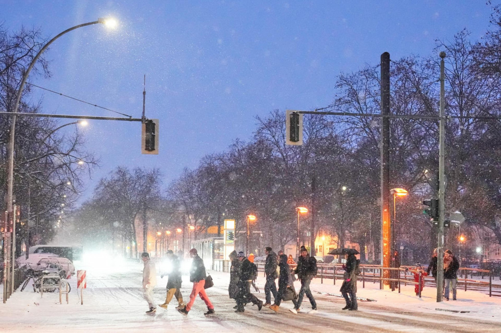 Ľudia kr&aacute;čaj&uacute; cez zasnežen&uacute; križovatku na ulici počas siln&eacute;ho sneženia v nemeckom Berl&iacute;ne. FOTO: TASR/AP