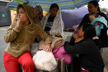 Rodinn&iacute; pr&iacute;slu&scaron;n&iacute;ci zadržan&yacute;ch sa schov&aacute;vaj&uacute; pred dažďom a čakaj&uacute; pred v&auml;zensk&yacute;m centrom N&aacute;rodnej pol&iacute;cie v z&oacute;ne sedem, zatiaľ čo venezuelsk&aacute; vl&aacute;da pokračuje v prep&uacute;&scaron;ťan&iacute; v&auml;zňov, ktor&eacute; podľa advokačn&yacute;ch skup&iacute;n a rod&iacute;n prebieha pomaly, v Caracase vo Venezuele. FOTO: Reuters