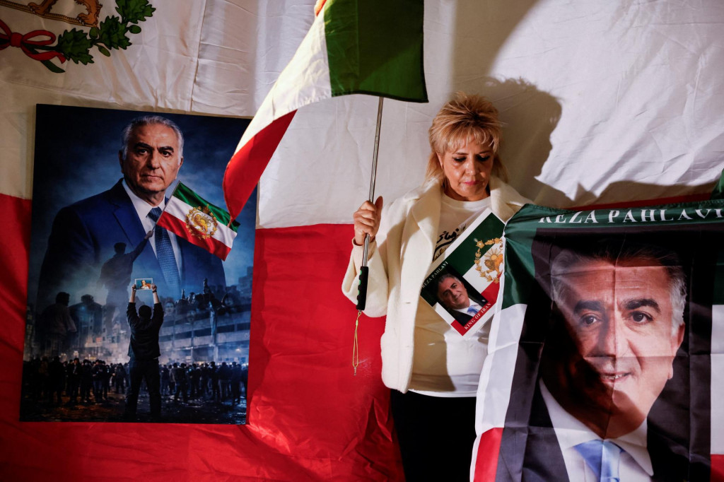 Žena drž&iacute; vlajku a fotografiu Rezu Pahlav&iacute;ho, exilov&eacute;ho syna posledn&eacute;ho ir&aacute;nskeho &scaron;&aacute;ha, zatiaľ čo stoj&iacute; vedľa n&aacute;rodnej vlajky spred ir&aacute;nskej revol&uacute;cie. FOTO: Reuters