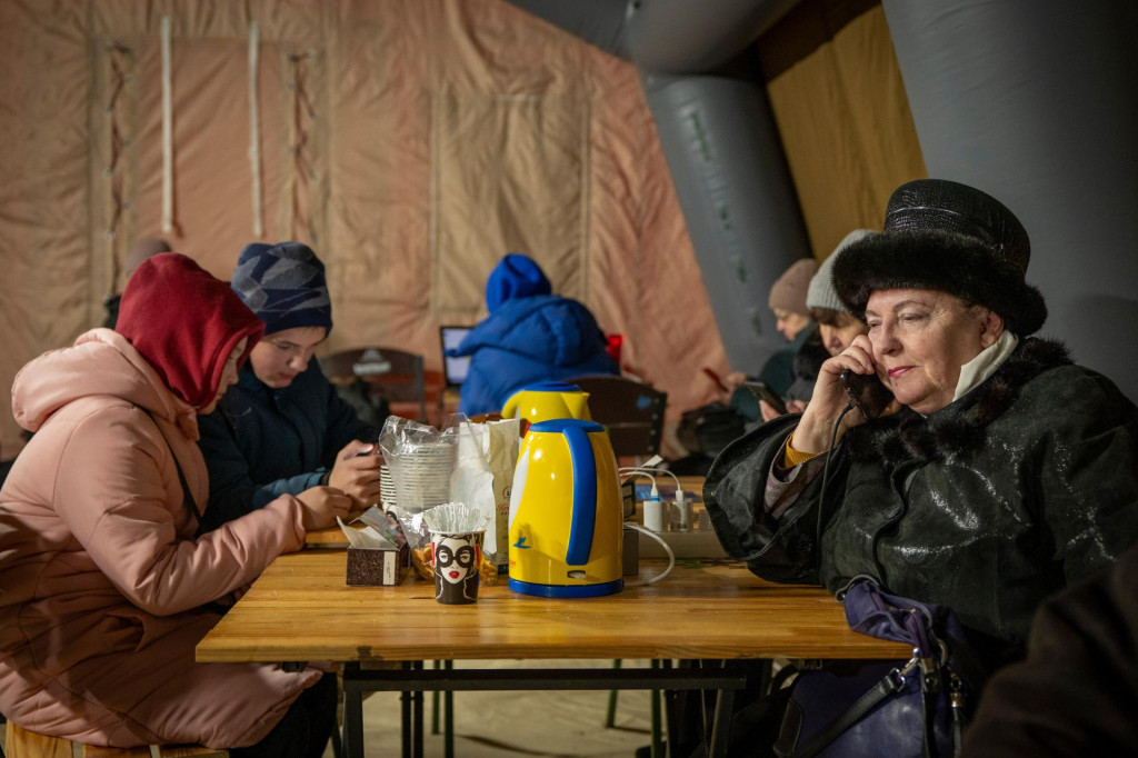 Ľudia sa zahrievaj&uacute; a nabijaj&uacute; si bat&eacute;rie v stane, ktor&yacute; postavili z&aacute;chrann&eacute; služby počas v&yacute;padku elektriny sp&ocirc;soben&eacute;ho pravideln&yacute;mi rusk&yacute;mi leteck&yacute;mi &uacute;tokmi na energetick&uacute; infra&scaron;trukt&uacute;ru krajiny v Kyjeve na Ukrajine. FOTO: TASR/AP