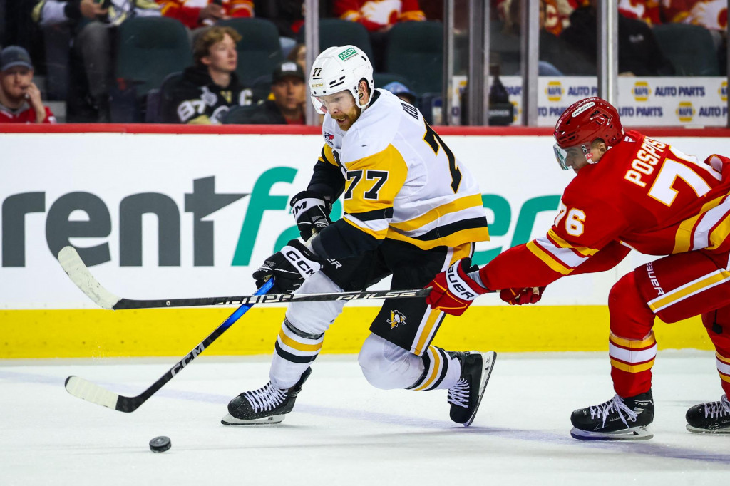Obranca Pittsburgh Penguins Brett Kulak (77) drž&iacute; puk proti centru Calgary Flames Martinovi Posp&iacute;&scaron;ilovi (76) počas tretej tretiny. FOTO: Sergei Belski/Imagn Images