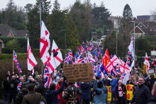 Demon&scaron;tranti držia vlajky a transparenty počas protestu proti využ&iacute;vaniu b&yacute;val&yacute;ch arm&aacute;dnych kas&aacute;rn&iacute; na ubytovanie žiadateľov o azyl v Crowborough vo V&yacute;chodnom Sussexe v Brit&aacute;nii. FOTO: Reuters
