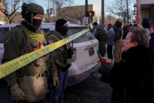 Feder&aacute;lni agenti stoja za policajnou p&aacute;skou, zatiaľ čo sa ľudia zhromažďuj&uacute; neďaleko miesta, kde Alex Pretti bol smrteľne postrelen&yacute; feder&aacute;lnymi agentmi. FOTO: Reuters